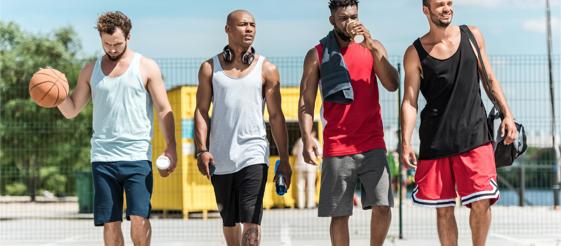 4 men side by side while one holds a basketball